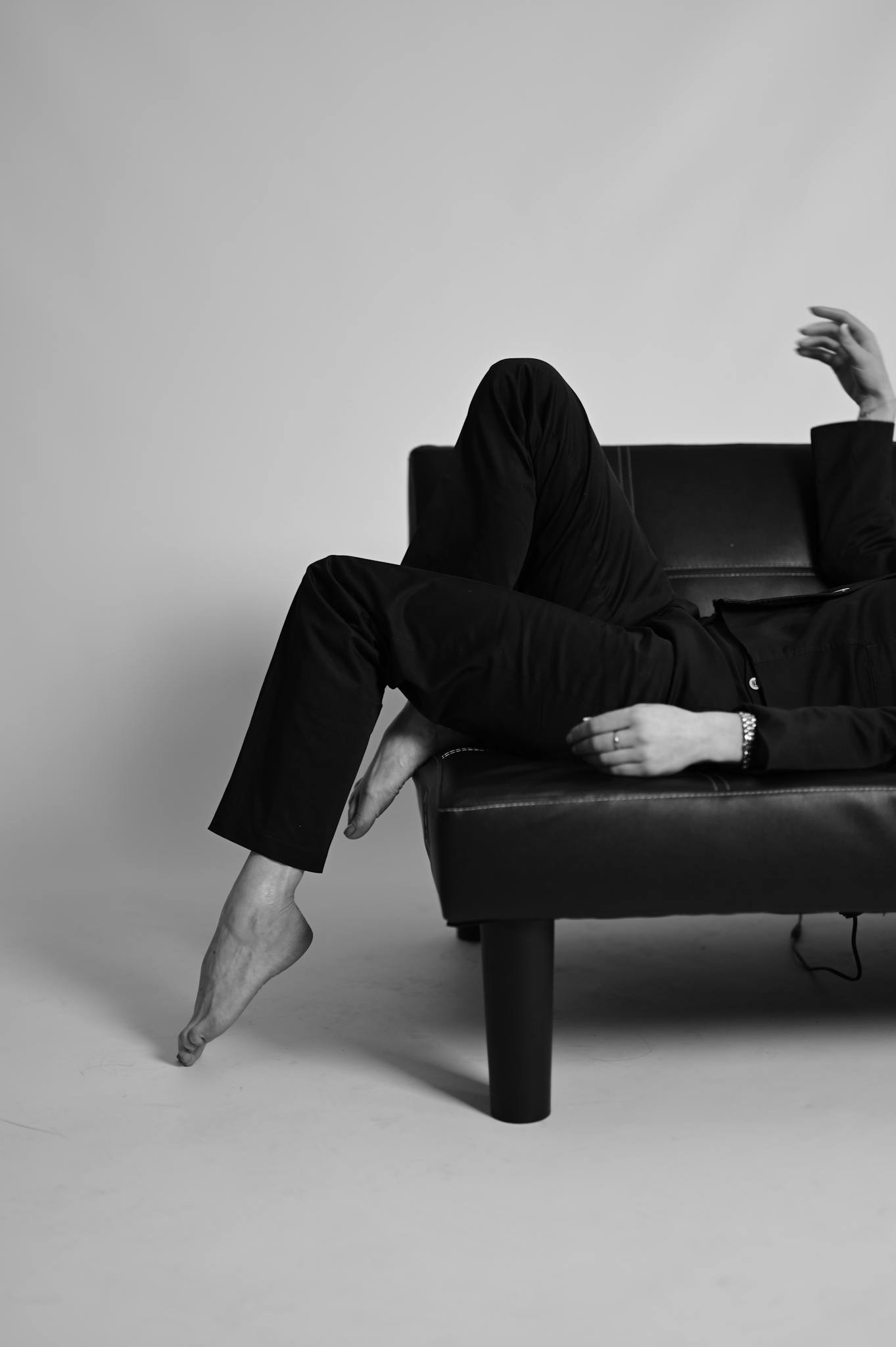 Black and white artistic fashion portrait featuring a person reclining on a couch, emphasizing style and mood.