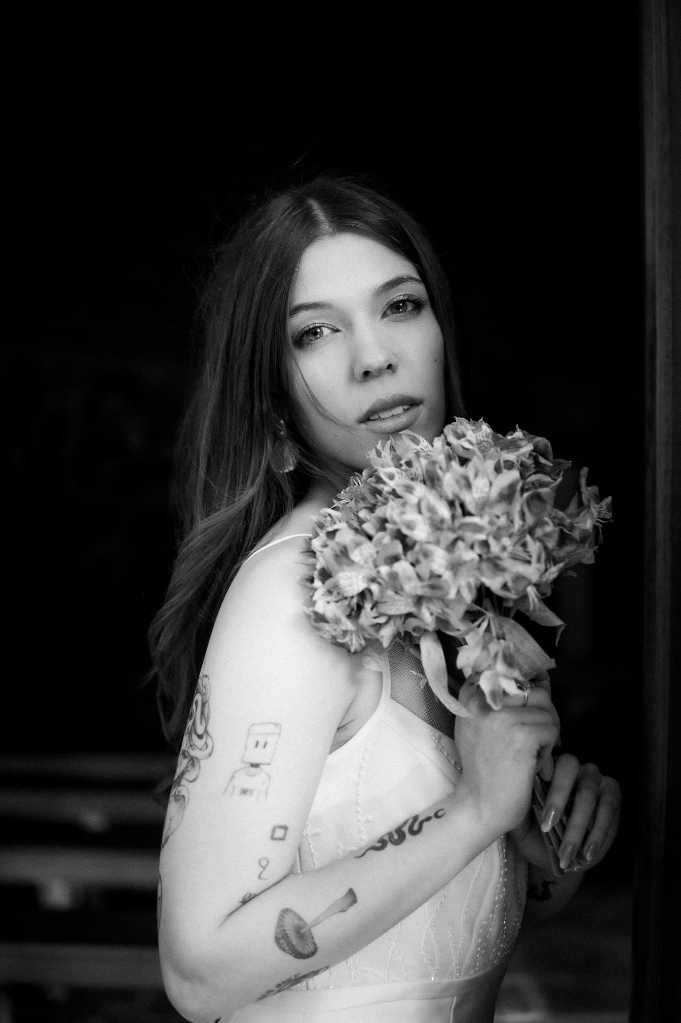 Charming black and white portrait of a bride holding flowers, expressing elegance.