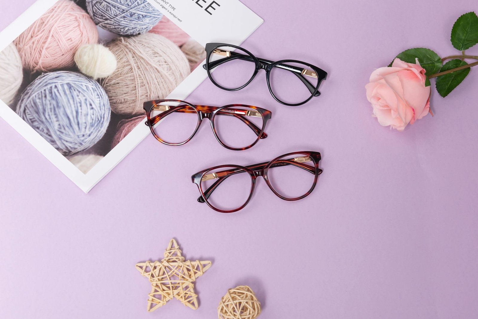 Modern eyeglasses arranged creatively on a purple backdrop with decorative elements.